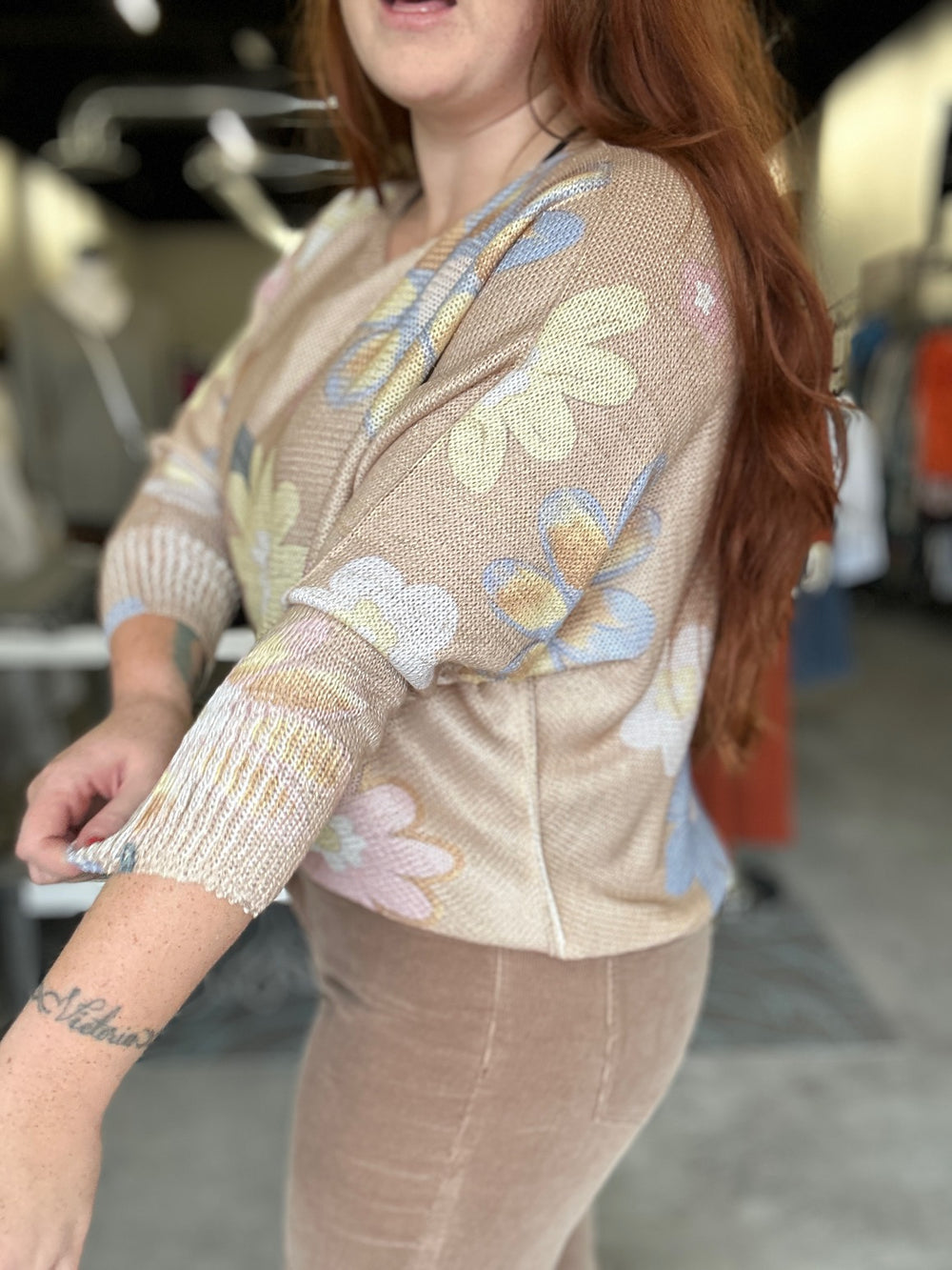 Person wearing a beige floral-patterned sweater in an indoor setting