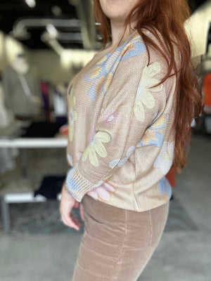 Person wearing a patterned beige sweater in an indoor setting
