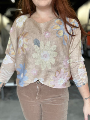 Person wearing a beige floral-patterned sweater in an indoor setting