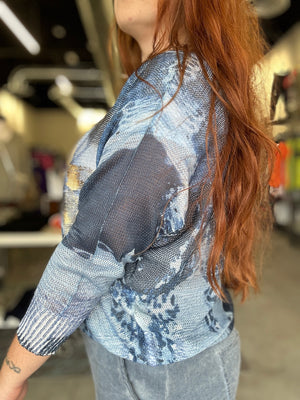 Person wearing a blue patterned top with a blurred background