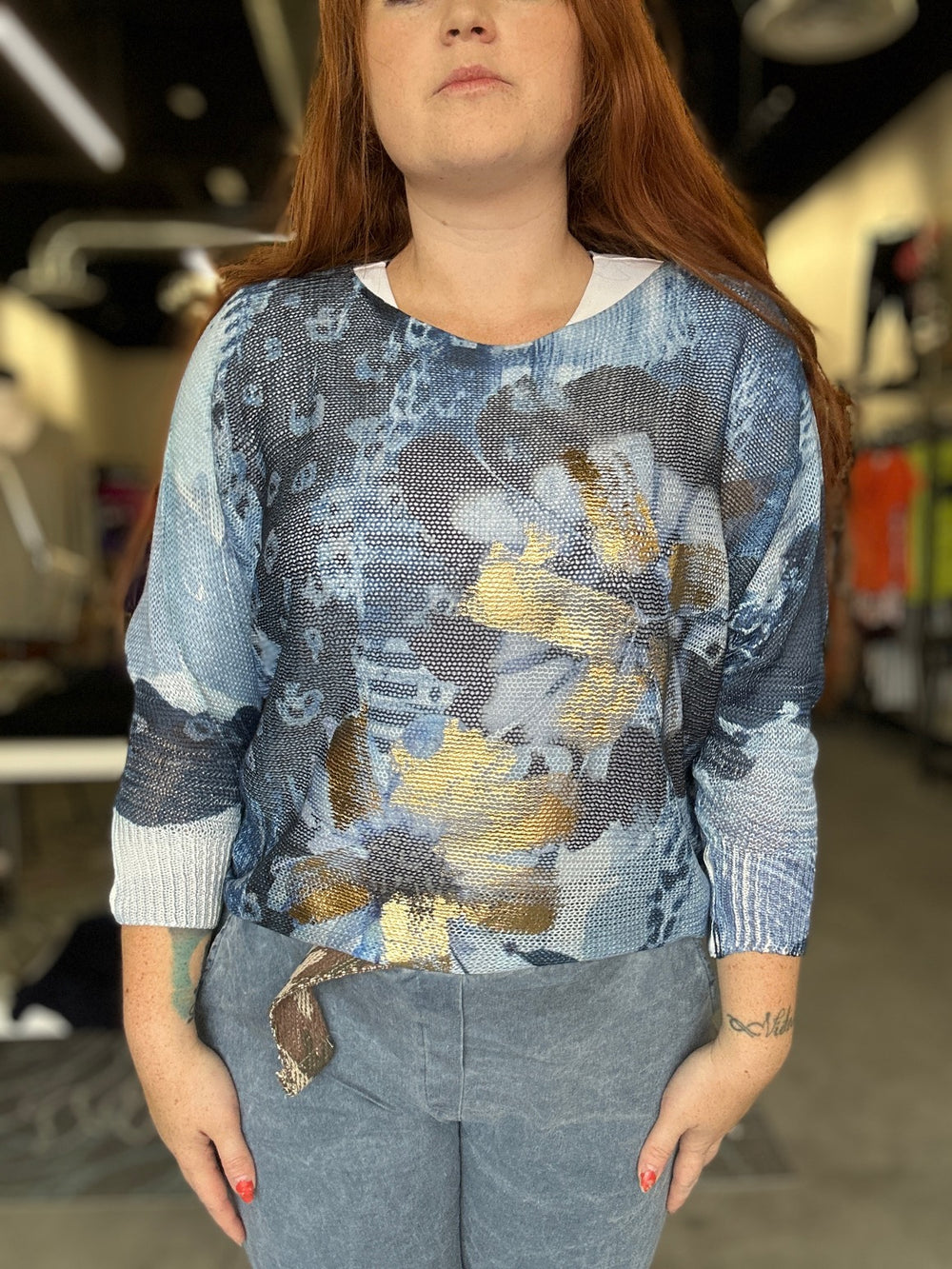 Person wearing a blue and gray with gold accent patterned sweater in an indoor setting
