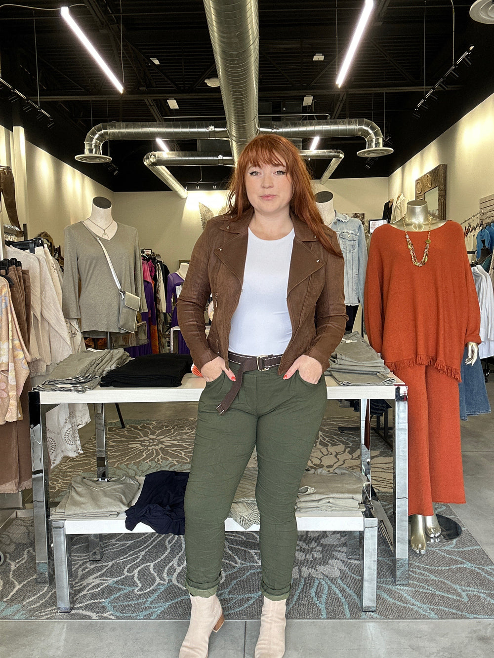 Woman standing in a store with clothing racks and mirrors around her