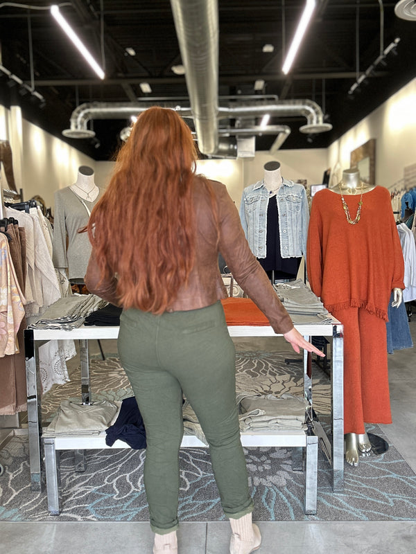 Person browsing through clothing in a store with racks and mannequins.