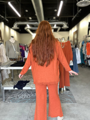 Woman in an orange outfit standing in a clothing store.