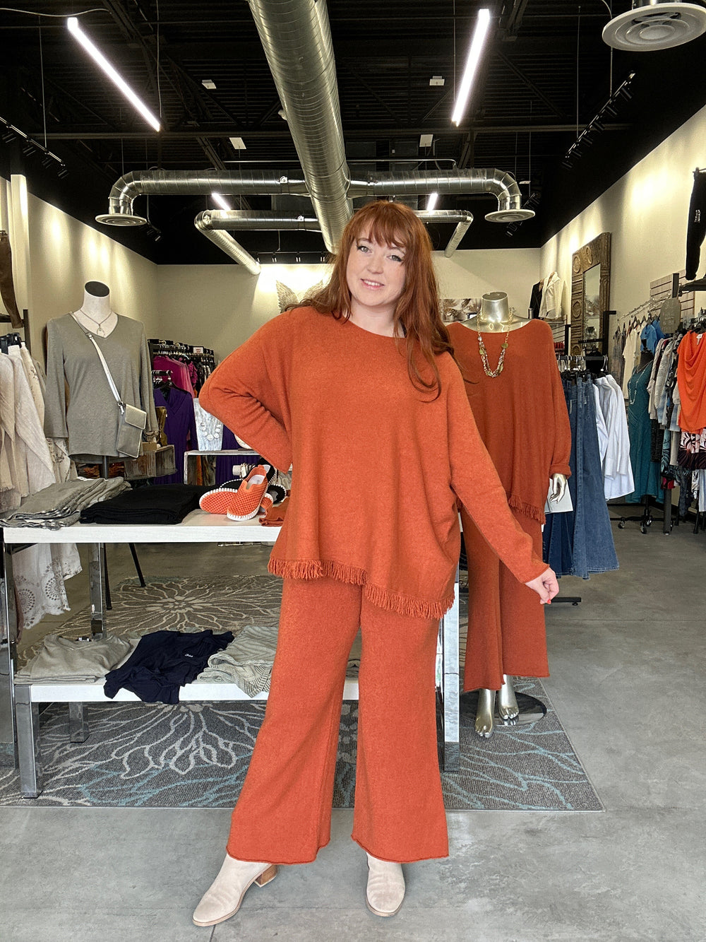 Person wearing a rust-colored poncho with fringe details indoors.